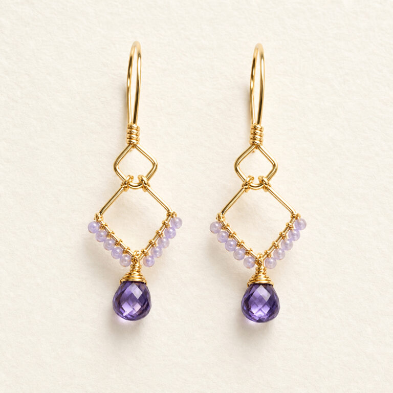 Handcrafted gold wire-wrapped amethyst earrings, flat lay on natural linen