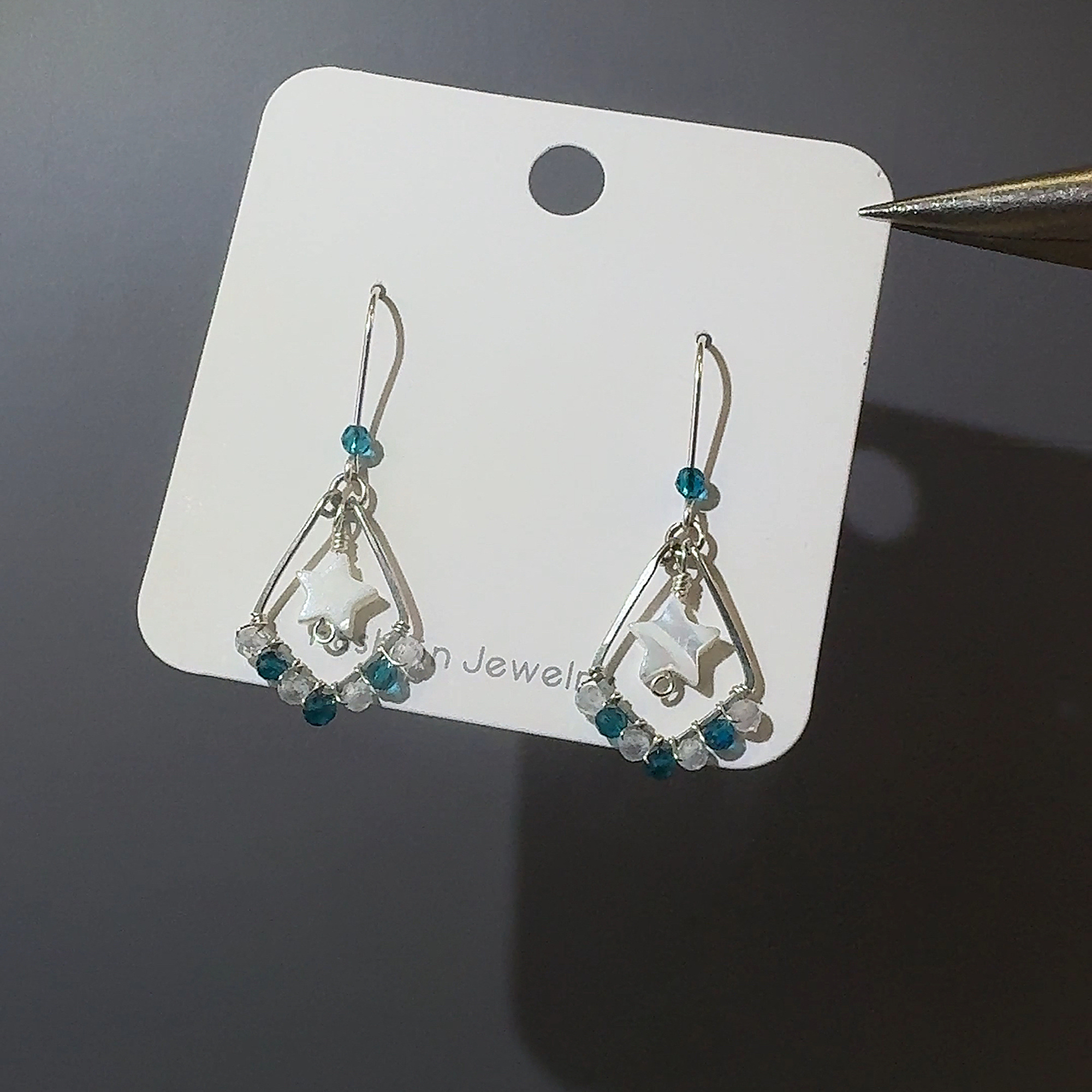 Teal star earrings on display card