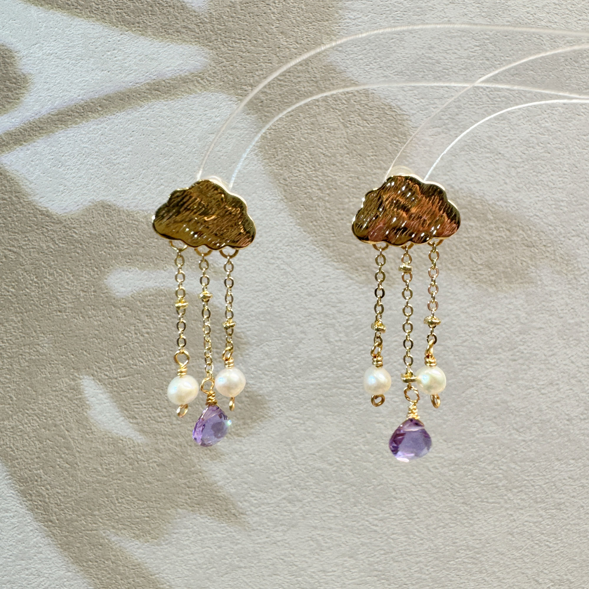 Pair of gold cloud earrings with pearl and purple gemstone drops
