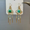 Pair of gold clover earrings with green stones, pearls and blue crystal tassels