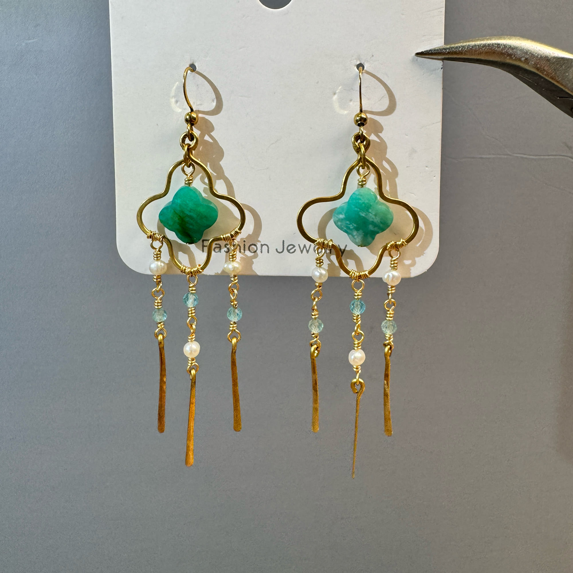 Pair of gold clover earrings with green stones, pearls and blue crystal tassels