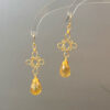 Gold filigree golden teardrop earrings on a display stand