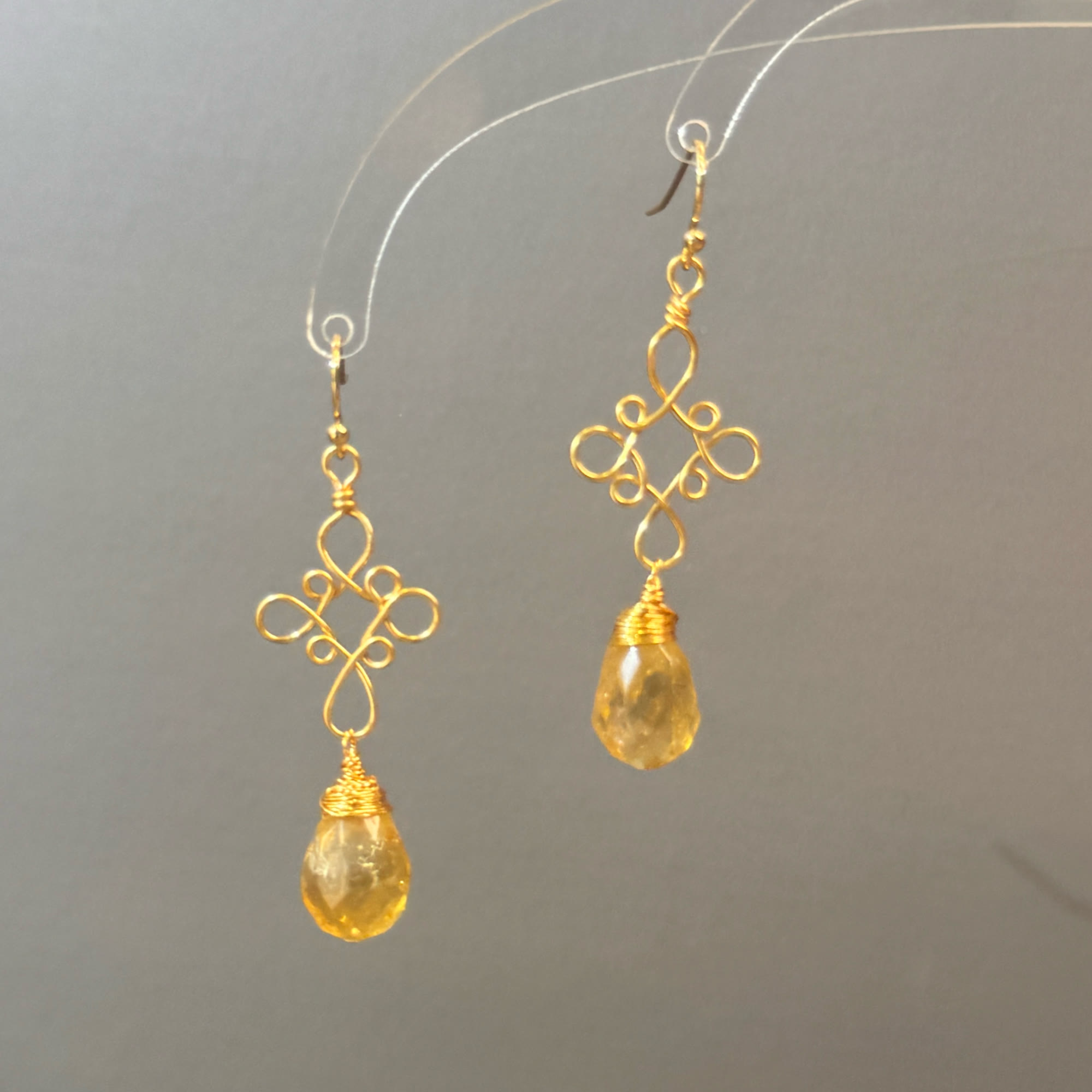 Gold filigree golden teardrop earrings on a display stand