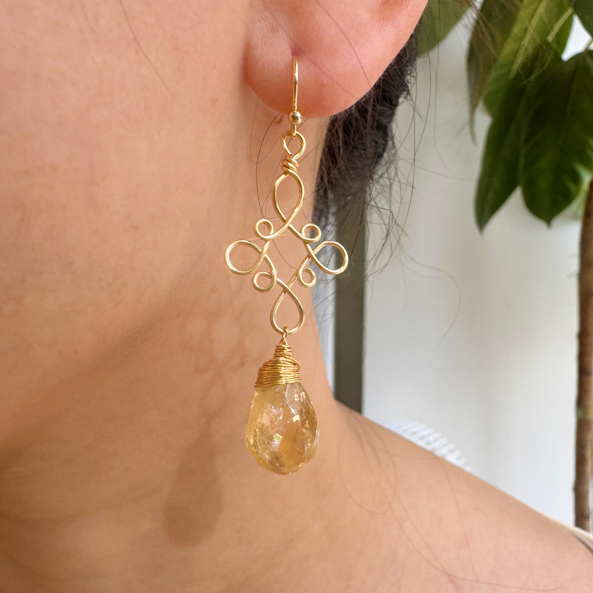 Gold filigree golden teardrop earring worn on the ear